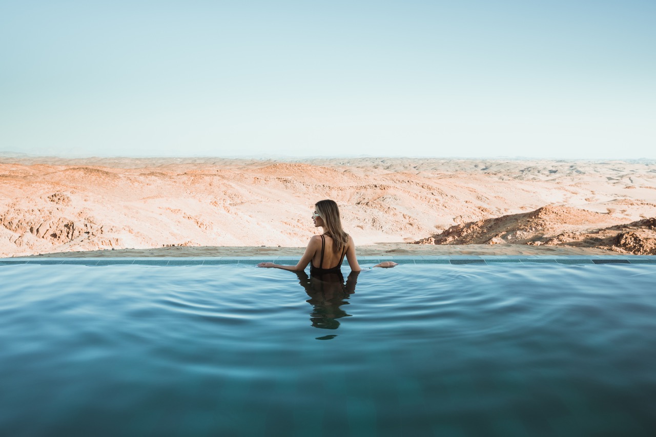 Woman enjoying a swim in a pool, surrounded by grand, majestic mountains.